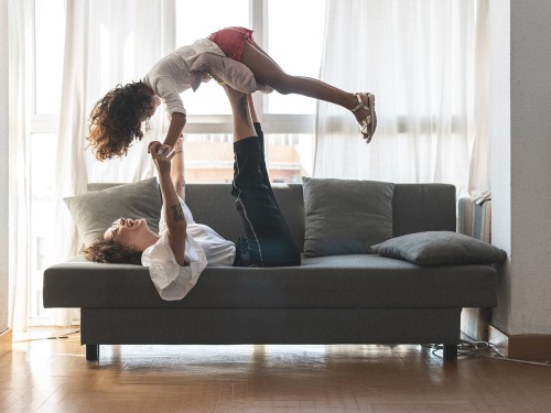 Mom laying on a couch, holding child up in the air.